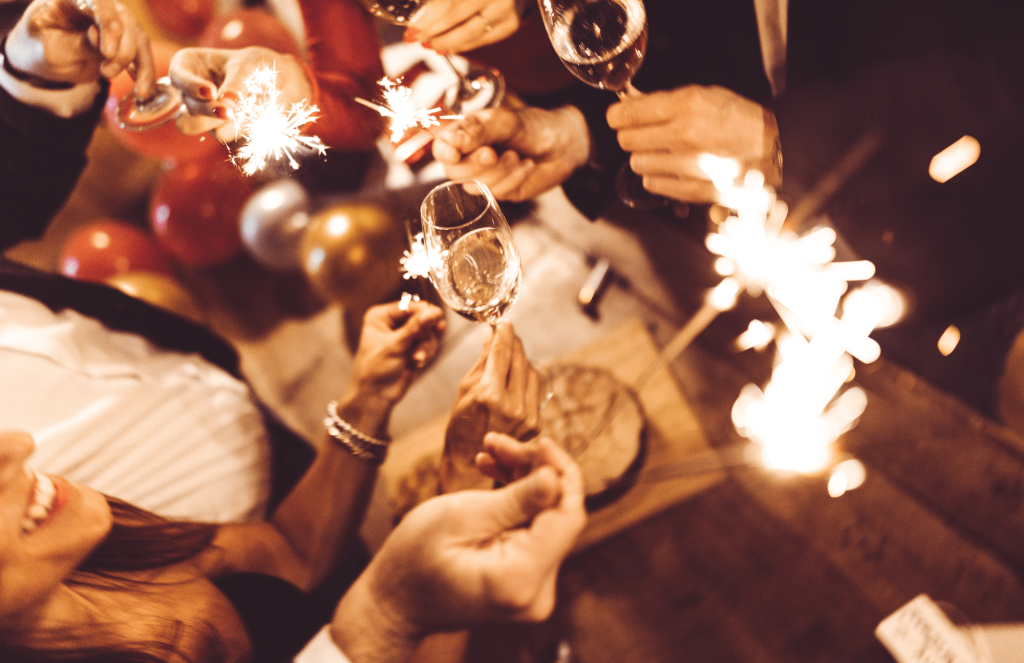 Gäste stoßen an Silvester mit Gläsern und Wunderkerzen an
